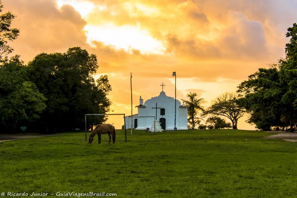 Imagem de um cavalo pastando em frente a igreja no centro de Quadrado.